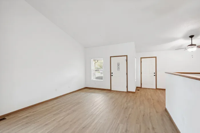 Bright and open living space with wooden flooring and vaulted ceilings.