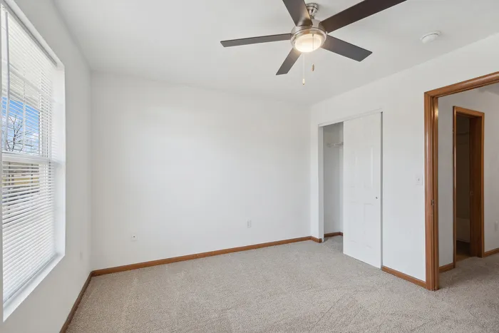 Inviting bedroom with soft carpet flooring, ceiling fan, and ample natural light.