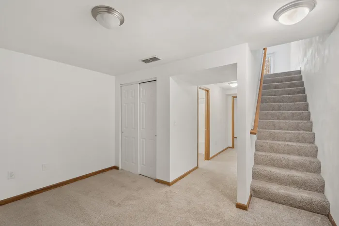A bright, carpeted stairway leads to a welcoming hallway with modern lighting.