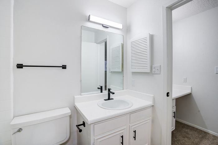Bright and stylish bathroom with white fixtures, a large mirror, and contemporary lighting.
