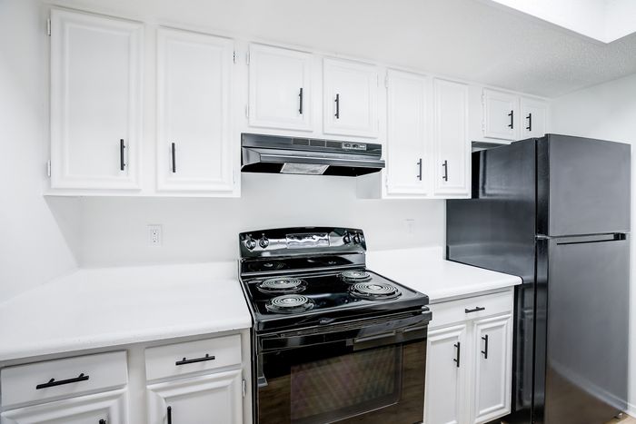 Modern kitchen with white cabinets, black appliances, and minimalist design.