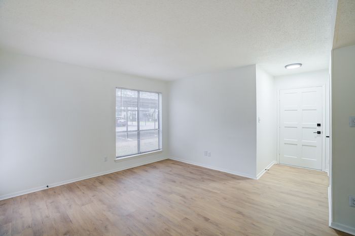 Sunlit room with wide window, elegant wooden flooring, and a stylish white door entrance.
