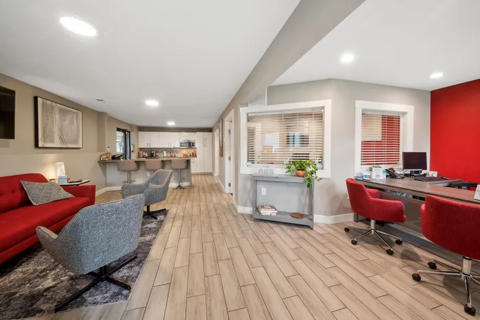 ReNew Foothills Bright, contemporary open-space apartment interior with stylish furniture, featuring a red sofa, gray chairs, a modern kitchen bar, and a sleek workspace.