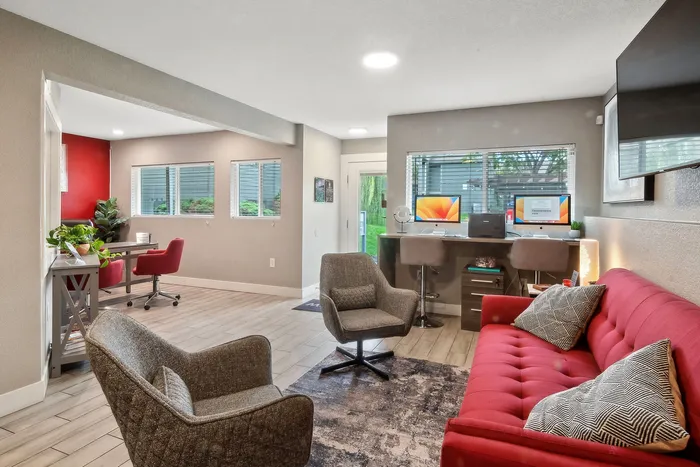 ReNew Foothills Contemporary living area with red sofa, comfortable chairs, and dual computer desk setup.