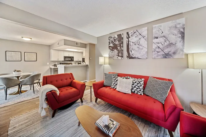 ReNew Foothills Bright and modern living room with red sofas, elegant dining area, and open kitchen design.