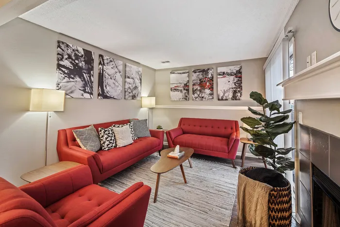 ReNew Foothills Stylish living room with vibrant red sofas, modern art pieces, and cozy lighting.