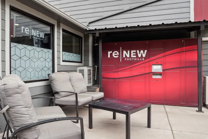 ReNew Foothills Cozy outdoor seating area at ReNew Foothills with modern armchairs and vibrant red feature wall.