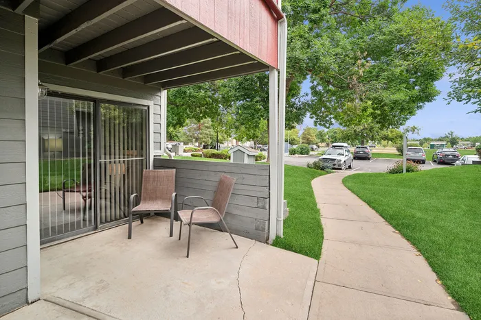 ReNew Foothills Cozy patio area with two chairs overlooking a lush green landscape and a path leading to a parking area.