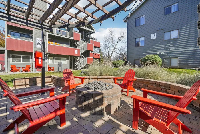 ReNew Foothills Inviting courtyard with red Adirondack chairs surrounding a cozy fire pit, perfect for gatherings.