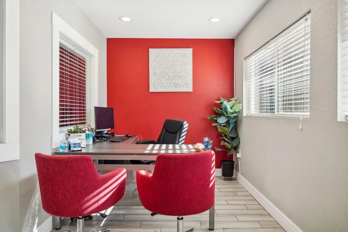 ReNew Foothills Modern home office featuring a sleek desk, vibrant red chairs, and a bold red accent wall.
