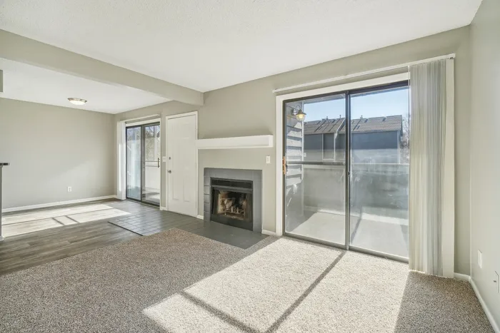 ReNew Foothills Spacious living room featuring a cozy fireplace, large windows, and sliding glass doors leading to a balcony.
