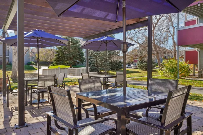 ReNew Foothills Inviting outdoor patio with elegant seating and purple umbrellas, surrounded by lush greenery.