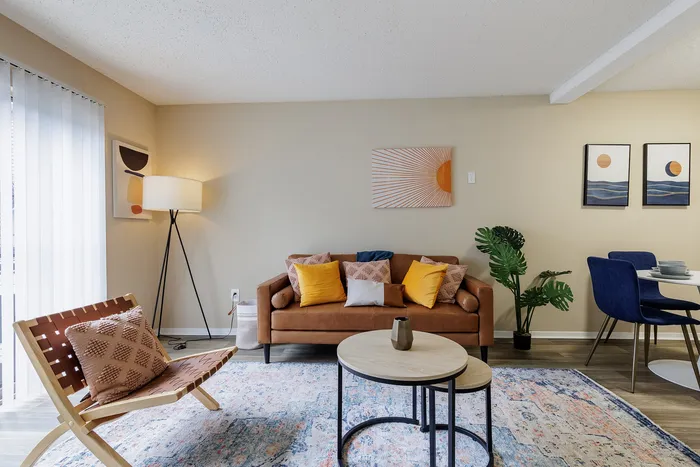Stylish living room with modern decor, featuring a cozy leather sofa, vibrant pillows, and a decorative floor lamp.