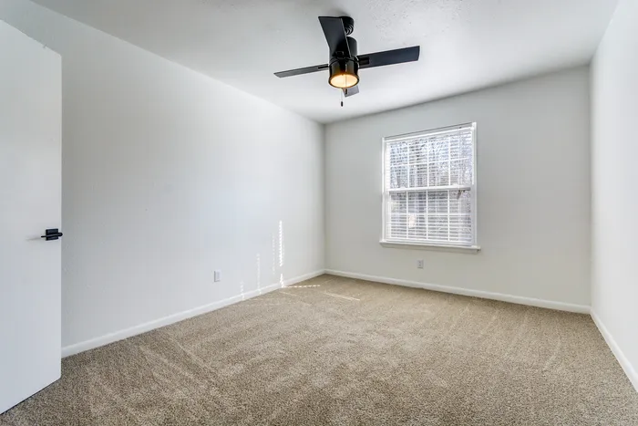 Bright, airy bedroom at ReNew on Cantrell featuring plush carpet and a modern ceiling fan, perfect for creating a cozy retreat.