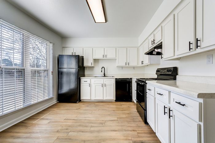 Bright and modern kitchen at ReNew on Cantrell with sleek black appliances, elegant white cabinetry, and large sunlit windows.