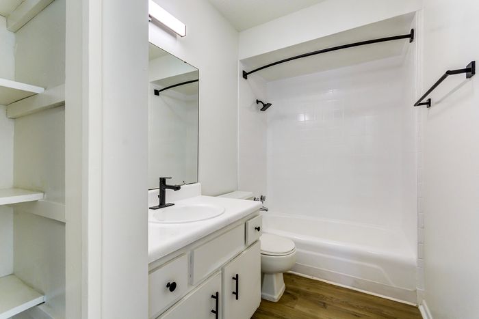 Contemporary bathroom at ReNew on Cantrell featuring sleek white cabinets, elegant black fixtures, and a bright shower area.