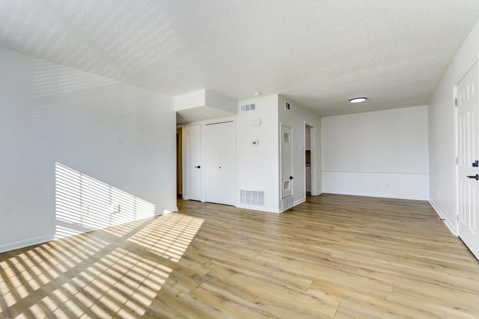 Bright and spacious living area at ReNew on Cantrell with elegant wooden flooring and ample natural light streaming through large windows.