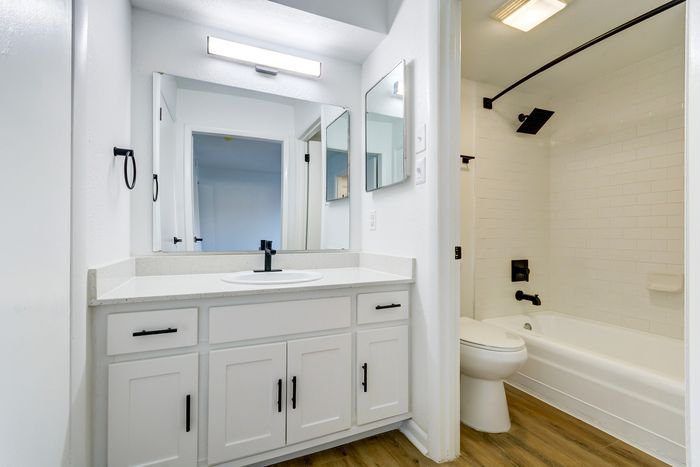 Sleek bathroom at ReNew on Cantrell with modern fixtures featuring a bright white vanity, elegant countertop, and efficient shower area.