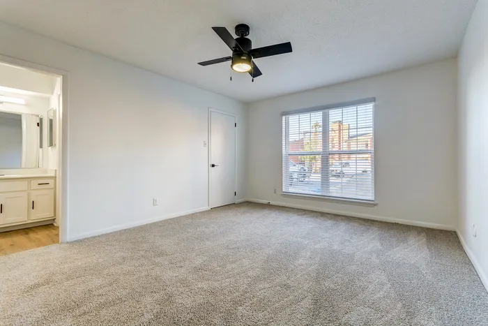 Bright and spacious bedroom at ReNew on Cantrell with a modern ceiling fan and large window offering ample natural light.
