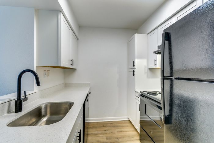 Modern kitchen at ReNew on Cantrell with sleek white cabinetry, stainless steel appliances, and elegant countertops in a contemporary apartment.