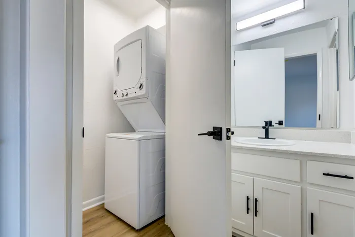 Modern apartment at ReNew on Cantrell featuring a convenient in-unit stacked washer and dryer next to a sleek bathroom with stylish fixtures and ample storage.