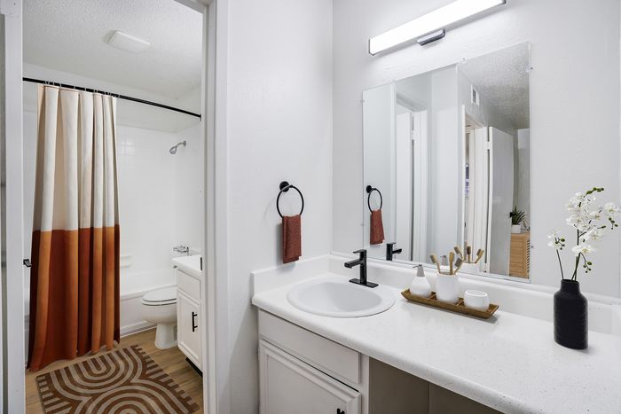 Modern bathroom with elegant fixtures, featuring a sleek vanity and a decorative floral arrangement, offering a serene and stylish space.