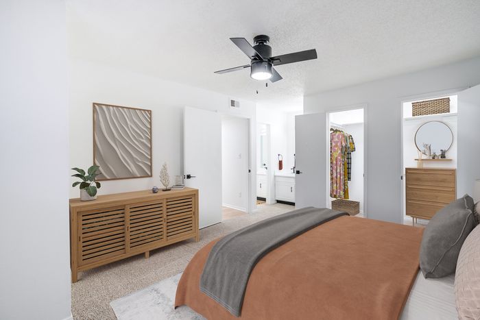 Bright and modern bedroom boasts elegant decor, spacious closets, and a stylish ceiling fan, perfect for a cozy retreat.