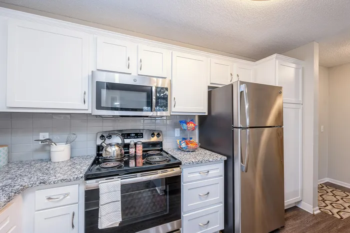 Modern kitchen with stainless steel appliances, elegant granite countertops, and stylish white cabinetry.