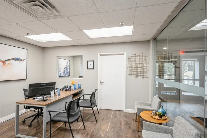 Modern office space featuring stylish decor, large desk, and comfortable seating area with contemporary artwork.