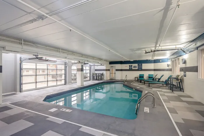 Inviting indoor pool with modern design, lounge chairs, and natural light, perfect for relaxation.