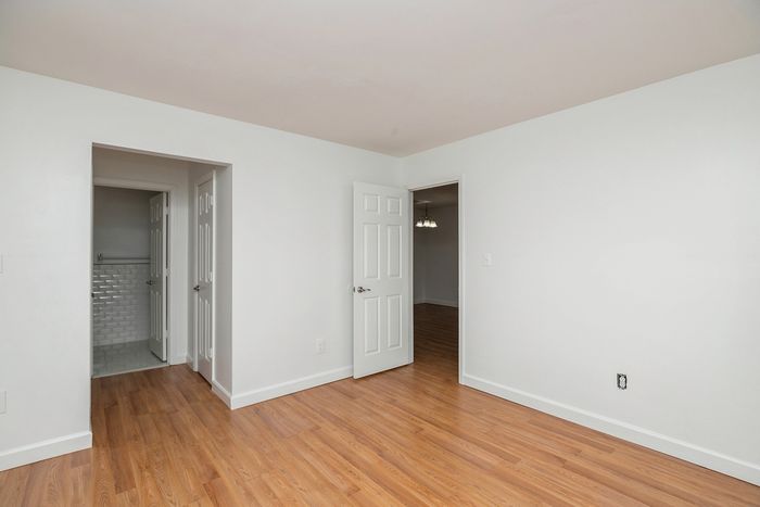 Bright, spacious room featuring polished hardwood floors and a glimpse into a modern bathroom, perfect for effortless living.