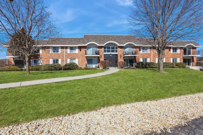 Charming two-story apartment complex with brick facade, balconies, and inviting green landscape.