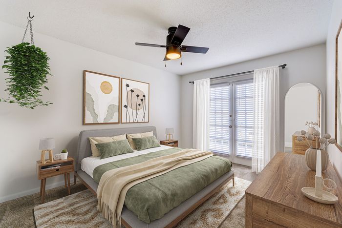 Inviting bedroom at ReNew on Cantrell with elegant decor, featuring a cozy double bed, modern furniture, and abundant natural light through stylish French doors.