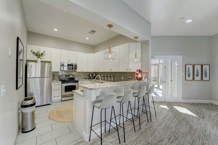 Modern kitchen with sleek stainless steel appliances, elegant pendant lighting, and a spacious breakfast bar with cozy seating.