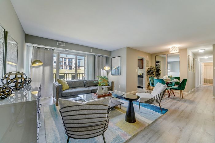 Bright, modern living space at ReNew White Marsh with elegant seating, floor-to-ceiling windows, and a cozy dining area, perfect for contemporary living.
