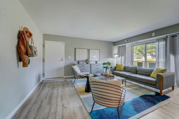Chic living room at ReNew White Marsh with modern decor, featuring a stylish grey sofa, vibrant accents, and large windows offering scenic views.
