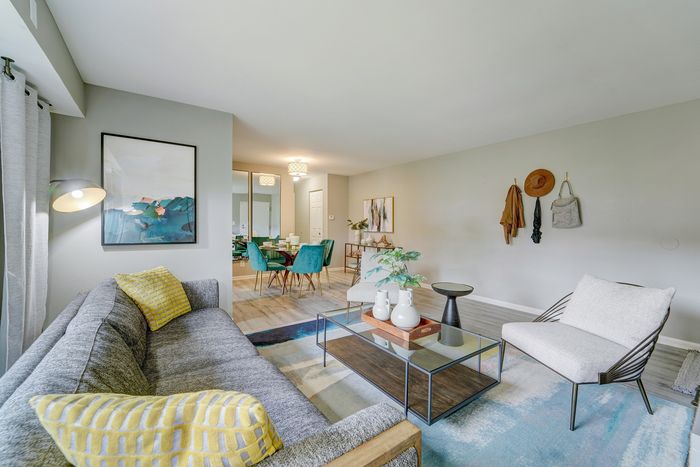 Modern living room at ReNew White Marsh with a cozy gray sofa, vibrant teal dining chairs, and chic decor, creating an inviting and stylish space.