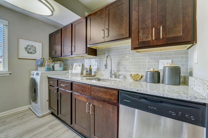 Elegant kitchen at ReNew White Marsh with rich wooden cabinets, modern backsplash, and built-in appliances, offering a blend of style and functionality.