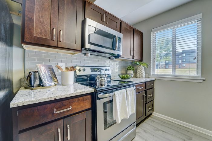 Modern kitchen at ReNew White Marsh with elegant dark wood cabinets, stainless steel appliances, and a bright window view.