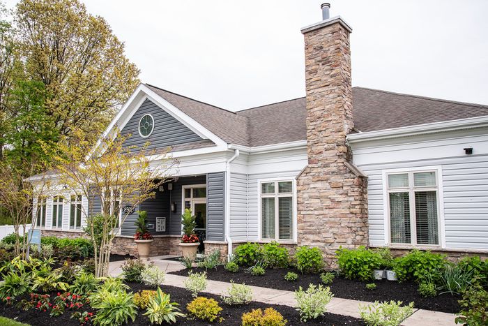 Charming single-story home with elegant stone facade, large windows, and lush landscaped garden.