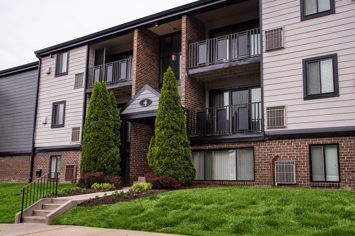 Charming apartment building with modern brick facade, private balconies, and lush landscaped entrance.