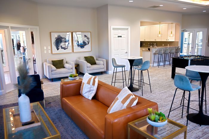 Elegant apartment lounge featuring contemporary decor, stylish seating, a modern open kitchen, and a foosball table.
