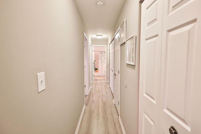 Elegant apartment hallway at ReNew White Marsh with modern flooring leading to a bright and inviting bathroom.