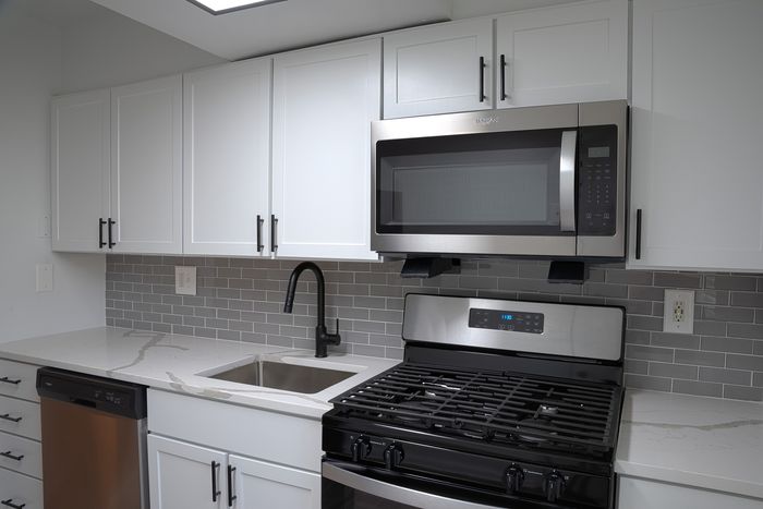Modern kitchen at ReNew White Marsh with sleek stainless steel appliances, elegant white cabinetry, and stylish gray tile backsplash.