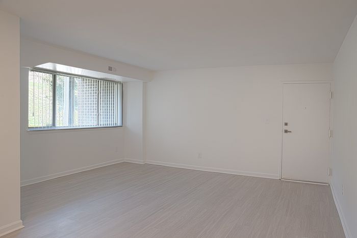 Bright, open-concept living space at ReNew White Marsh with sleek laminate flooring and large window offering natural light.