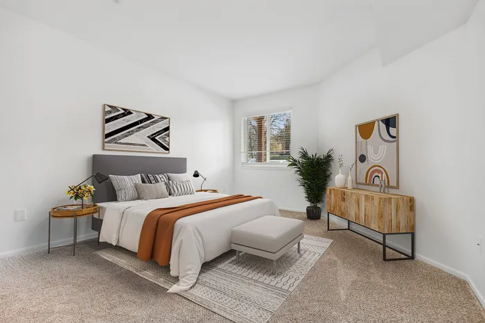 Elegant bedroom with plush carpeting, modern decor, stylish bed, and large windows inviting ample natural light.