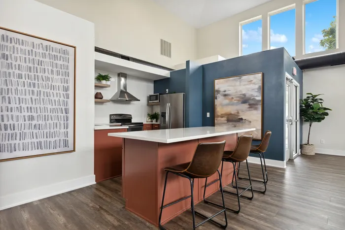 Elegant modern kitchen with stylish dark accents, featuring a spacious island, sleek cabinetry, and ample natural light from large windows.