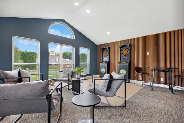 Bright and stylish living area with sleek modern furniture, large windows, and dartboards, accentuated by rich wood paneling.