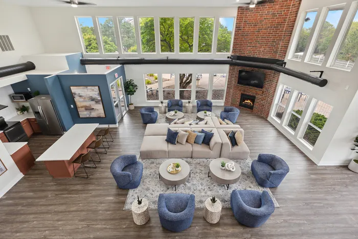 Spacious and inviting living area with modern design featuring ample seating, a cozy fireplace, high ceilings with large windows, and an open concept kitchen.