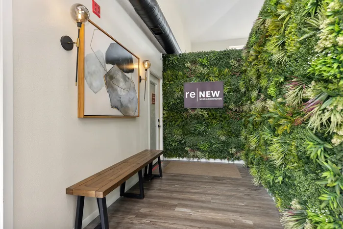 Modern apartment entrance featuring lush green vertical garden and chic wall art at ReNew West Bloomington.